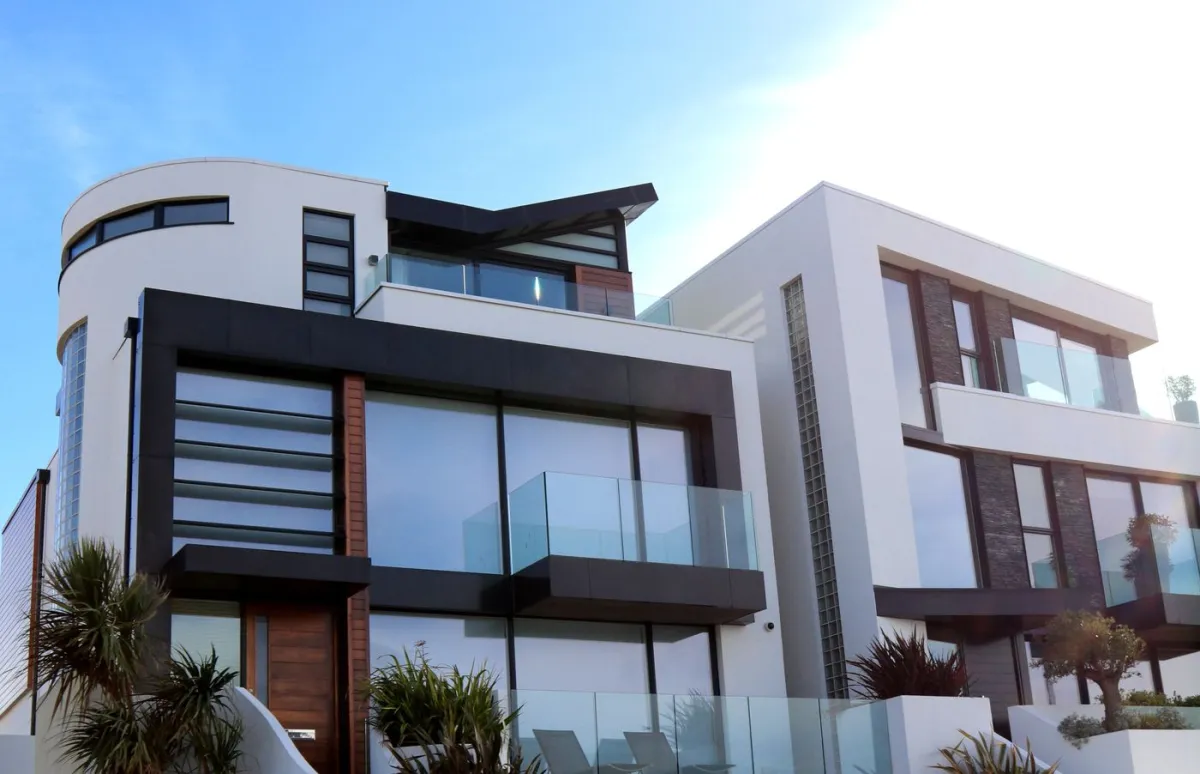 Two contemporary white and timber houses with glass balconies, seen from the street