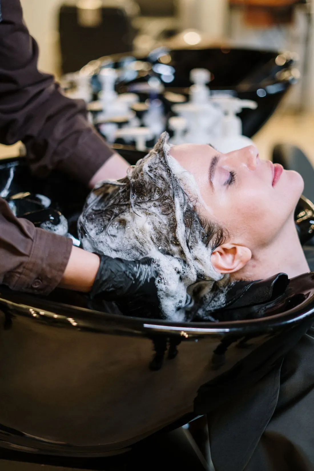 A client reclining at a salon basin during a shampoo and scalp treatment